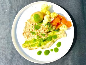 Pan-fried white fish fillet with dill oil, new potatoes, cauliflower, carrots, and chanterelle sauce on a plate.