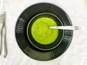 Creamy pea puree made with frozen peas, onion, vegetable stock, and cream, served in a dark grey bowl.