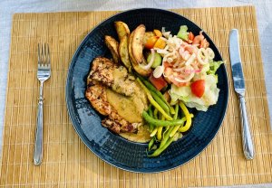 Grilled chicken with apple-mustard glaze, roasted potatoes, green beans, and a fresh mixed salad on a plate.