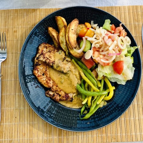 Grilled chicken with apple-mustard glaze, roasted potatoes, green beans, and a fresh mixed salad on a plate.