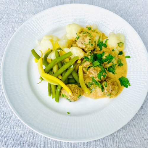 Finnish meatballs in creamy sauce served with boiled cauliflower and green and yellow beans