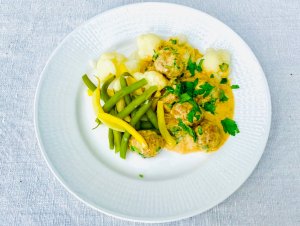 Finnish meatballs in creamy sauce served with boiled cauliflower and green and yellow beans