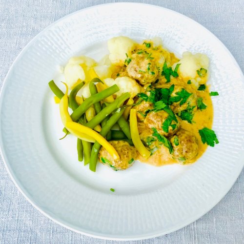 Finnish meatballs in creamy sauce served with boiled cauliflower and green and yellow beans