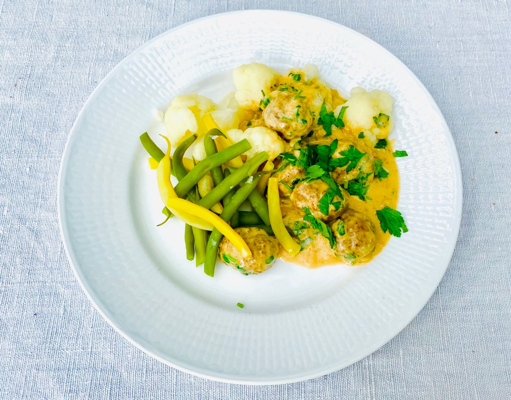 Finnish meatballs in creamy sauce served with boiled cauliflower and green and yellow beans