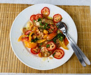 Fresh tomato salad with red, yellow and brown tomatoes, garlic and parsley