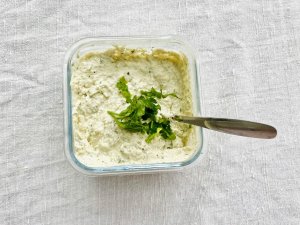 White pesto with walnuts, cottage cheese, Parmesan, and parsley in a glass jar.