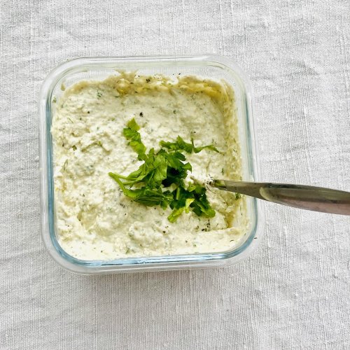 White pesto with walnuts, cottage cheese, Parmesan, and parsley in a glass jar.