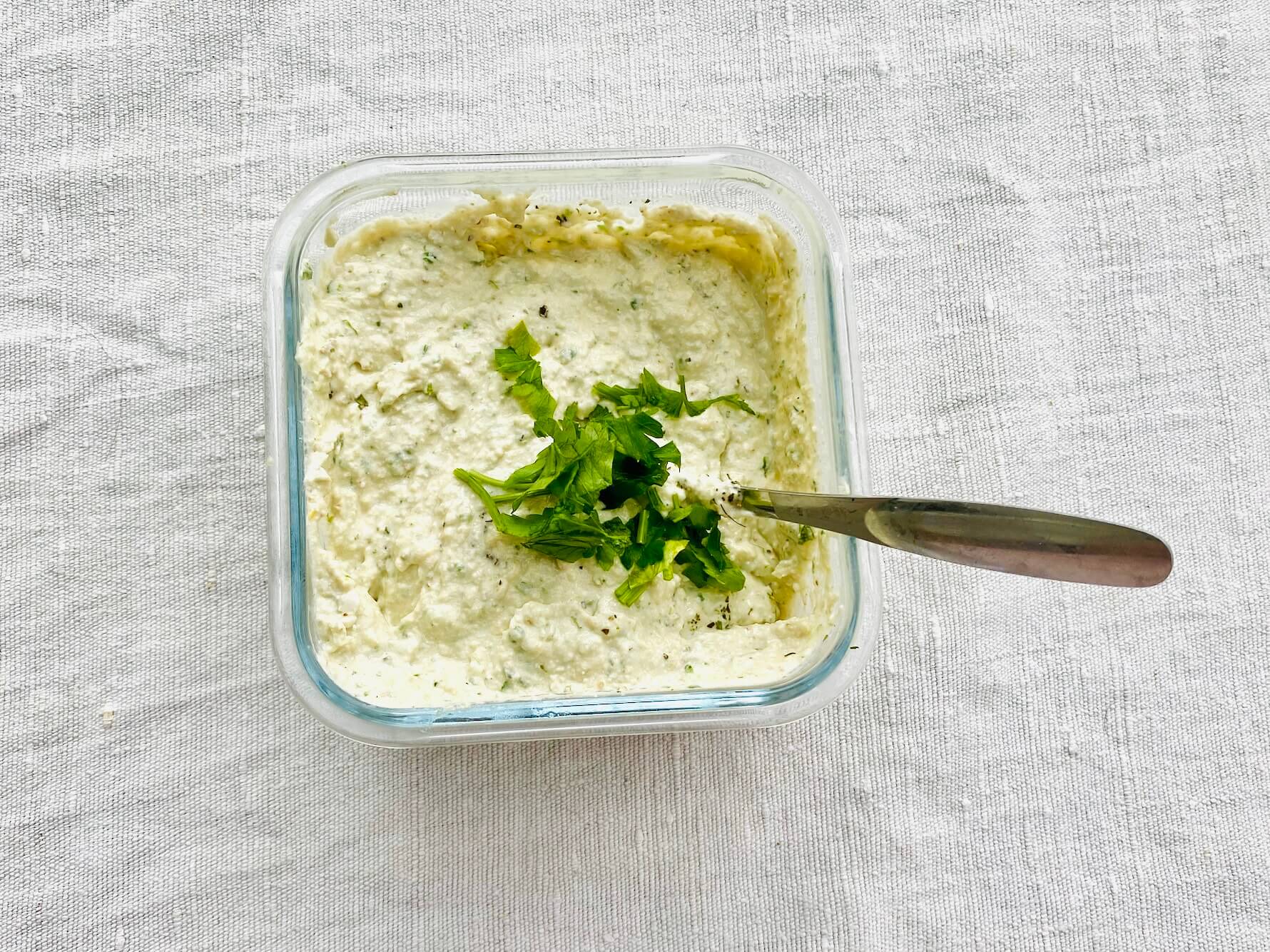 White pesto with walnuts, cottage cheese, Parmesan, and parsley in a glass jar.